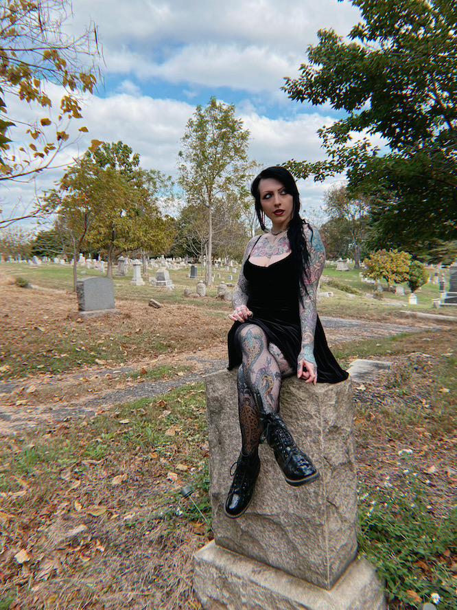 vampire coyly sitting on a headstone in a cemetery
