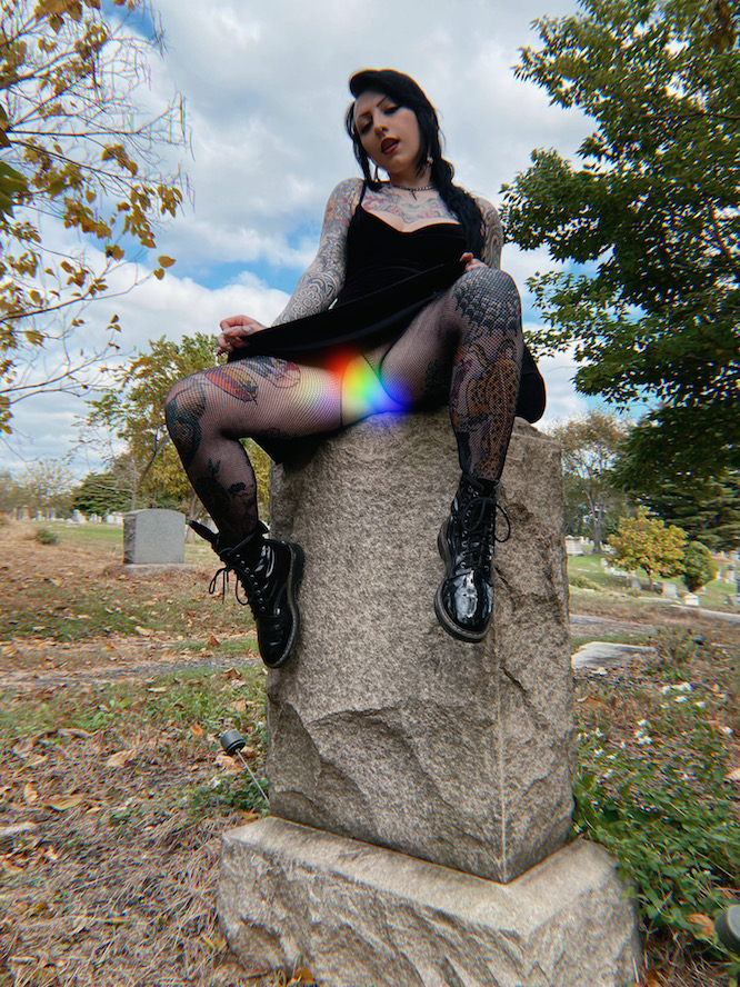 vampire wearing crotchless fishnets sitting on a headstone in a cemetery
